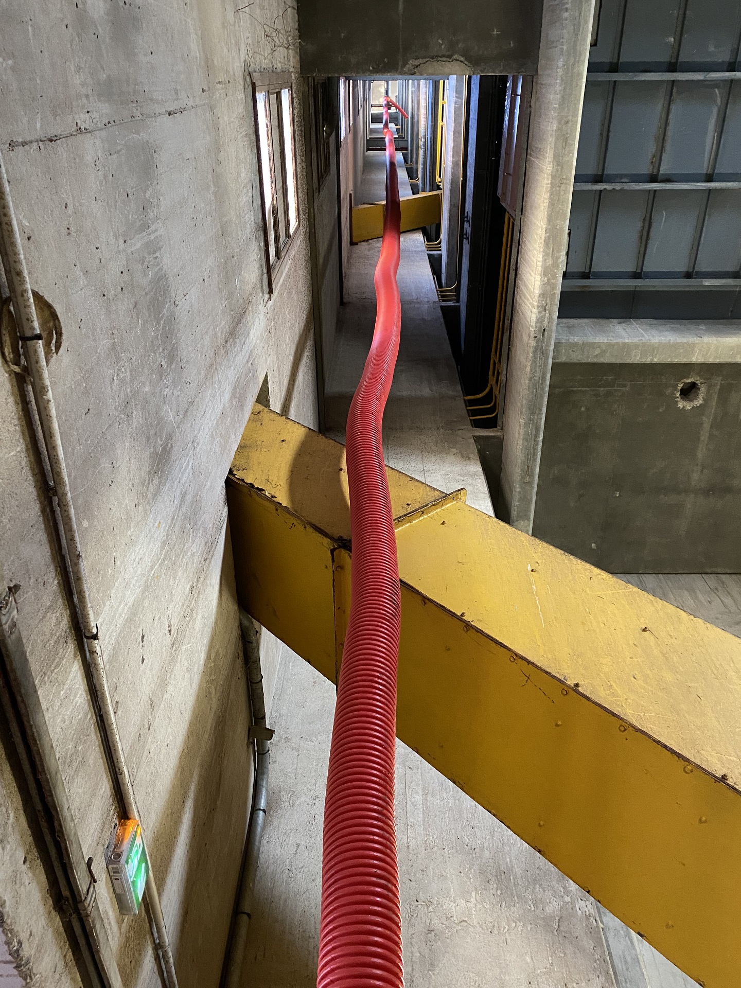 Une longueur de tuyau supplémentaire est déroulé dans la galerie technique d'un bâtiment industriel afin d'aspirer à distance de l'aspiratrice.