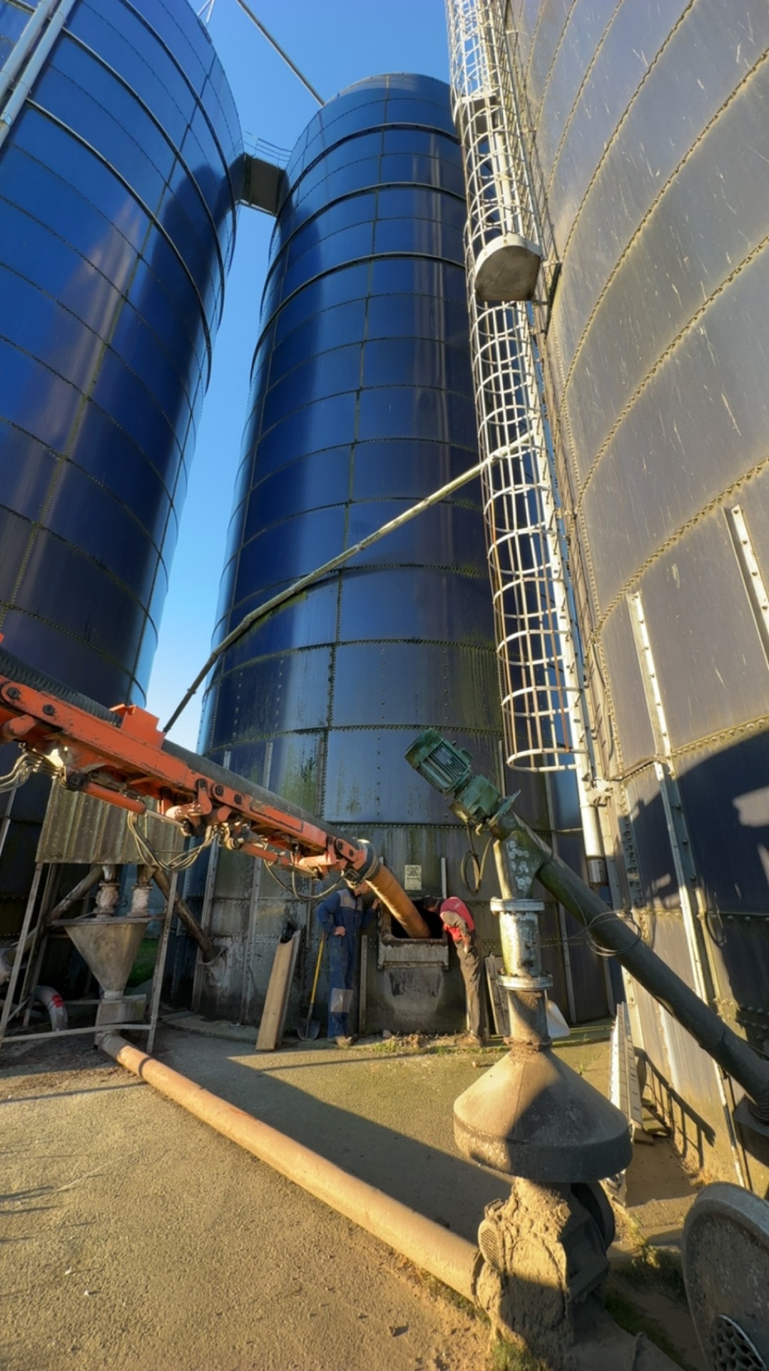 Vider un silo industriel par aspiration : le bras de l'aspiratrice excavatrice s'insère dans la trappe basse du silo afin de permettre l'aspiration du contenu du silo.