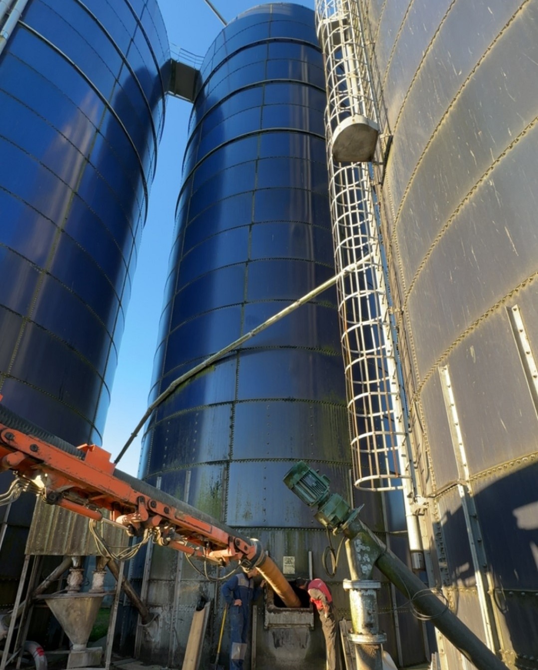 Vider un silo industriel par aspiration : le bras de l'aspiratrice excavatrice s'insère dans la trappe basse du silo afin de permettre l'aspiration du contenu du silo.
